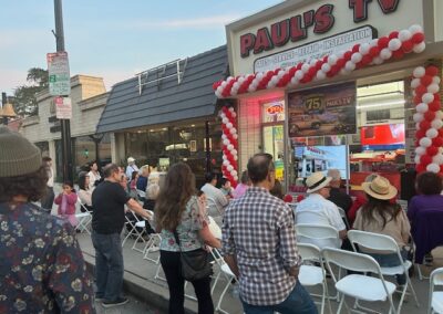 People watching video in storefront window of Paul's TV