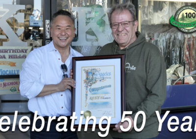 Councilmember John Lee presents handmade City Certificate of Congratulations to Jake, owner of Kenn Cleaners